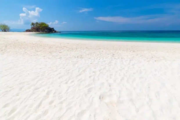 Pasir putih di tepi laut dengan batu dan bahan alami